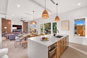 A modern kitchen with a central island, pendant lighting, and a view of the outdoors. - Vilano Villa | Pool | Wellness | Water View | Golf (St. Augustine)