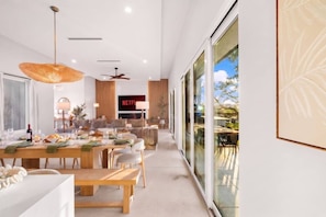 A modern interior with a dining area, a living room, and a large glass door leading to an outdoor space.