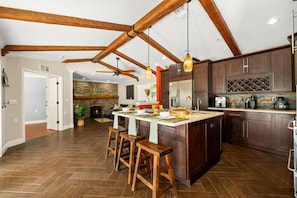 A spacious kitchen with a large island, dark wooden cabinets, and a stone fireplace. - 6-Acre Lakeside Retreat | Kayaks, Jacuzzi & Stunning Sunrises (Sebring)