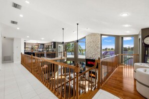 A spacious interior with a wooden staircase, a stone pillar, and a view of the outdoors. - Lakefront Estate 16ppl |Pool| Sauna| Dock| Hot Tub (Sebring)