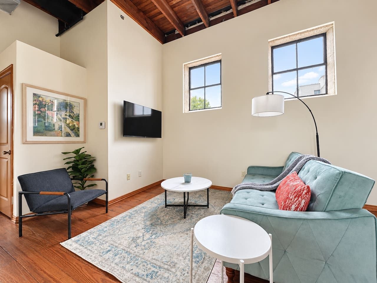 A living room with a sofa, a chair, a coffee table, and a TV mounted on the wall.