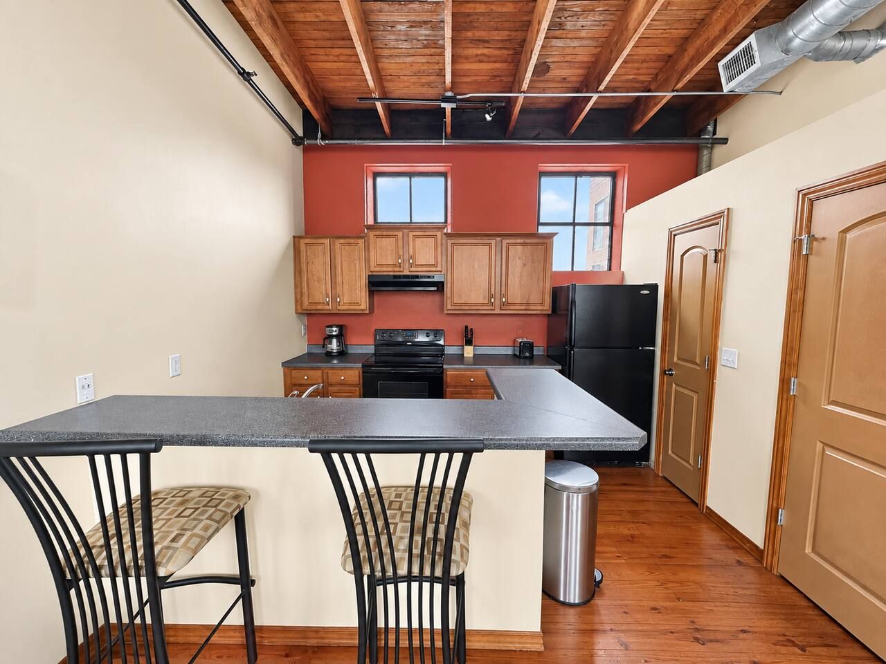 A compact kitchen with wooden cabinets, a central island, and a bar-style seating area.