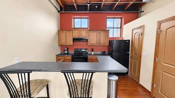 A compact kitchen with wooden cabinets, a central island, and a bar-style seating area.
