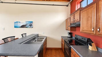 A kitchen with a central island, wooden cabinets, and a red accent wall.