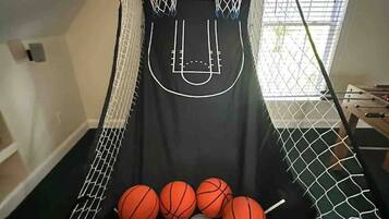 Un panier de basket avec un filet, quatre ballons de basket et un panneau de commande fixé au mur.