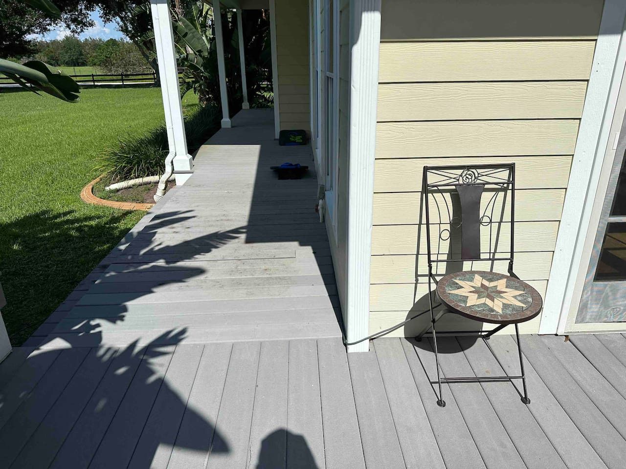 A porch with a chair, a pathway leading to a house, and a lawn.