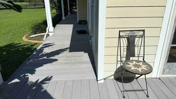 A porch with a chair, a pathway leading to a house, and a lawn.