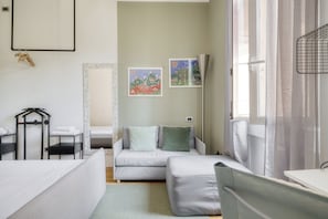 A bedroom with a bed, a bedside table, a chair, a wardrobe, and a window with curtains. - Bright Apt 1BR in the Heart of Isola (Milano)
