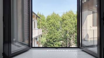 A window with a view of a tree-lined street and buildings.