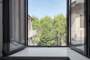 Una ventana con vista a una calle arbolada y edificios.