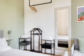 Habitació d'hotel amb llit, escriptori, cadira, mirall i penjador de tovalloles.
