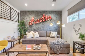 Una sala moderna con un sofá seccional, una mesa de centro y un letrero de neón instalado en la pared.