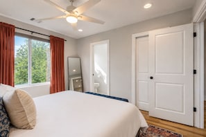 A bedroom with a bed, a ceiling fan, a window with curtains, a door, and a mirror. - Vibrant, Spacious Austin Getaway, 4BR, Sleeps 10, Near Downtown & Mueller (Austin)