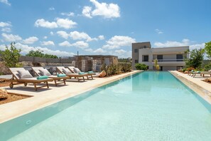 Ein Schwimmbecken mit Liegestühlen und einem modernen Gebäude im Hintergrund.