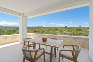 A terrace with a table and chairs, overlooking a hilly landscape. - Le Mont Blanc | Large Group Villa Sleeps 13 Guests (Kounoupidiana)