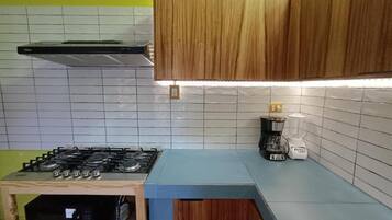 Cozinha equipada com fogão a gás, cafeteira e armários de madeira.