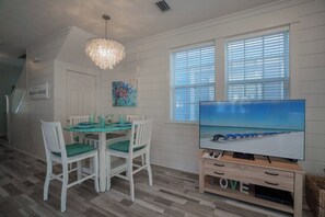 A dining area with a table and chairs, a television on a wooden stand, and a staircase leading to another level. - Florida Fun on 30A steps from Rosemary & Alys Beach Fun Lagoon Pool 4 Free Bikes (Panama City Beach)