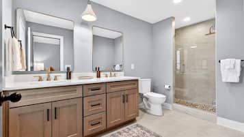 A modern bathroom with a double vanity, a glass shower enclosure, and a large mirror.