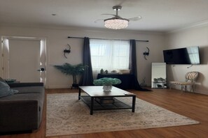Ein Wohnzimmer mit Sofa, Couchtisch, Fernseher und Deckenventilator.