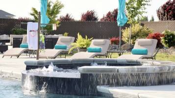 Un espace piscine avec des chaises longues et un jacuzzi.