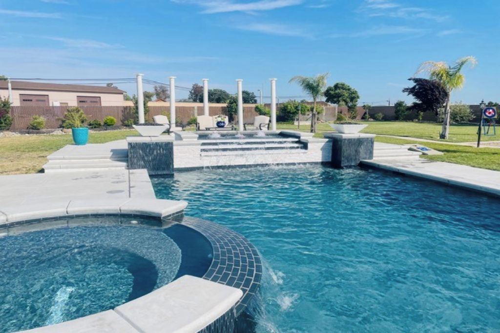 Una piscina con hidromasaje, escalones y zona de terraza.