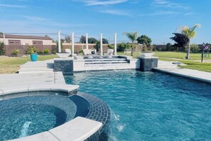 Ein Schwimmbecken mit Whirlpool, Stufen und einer Terrassenfläche.