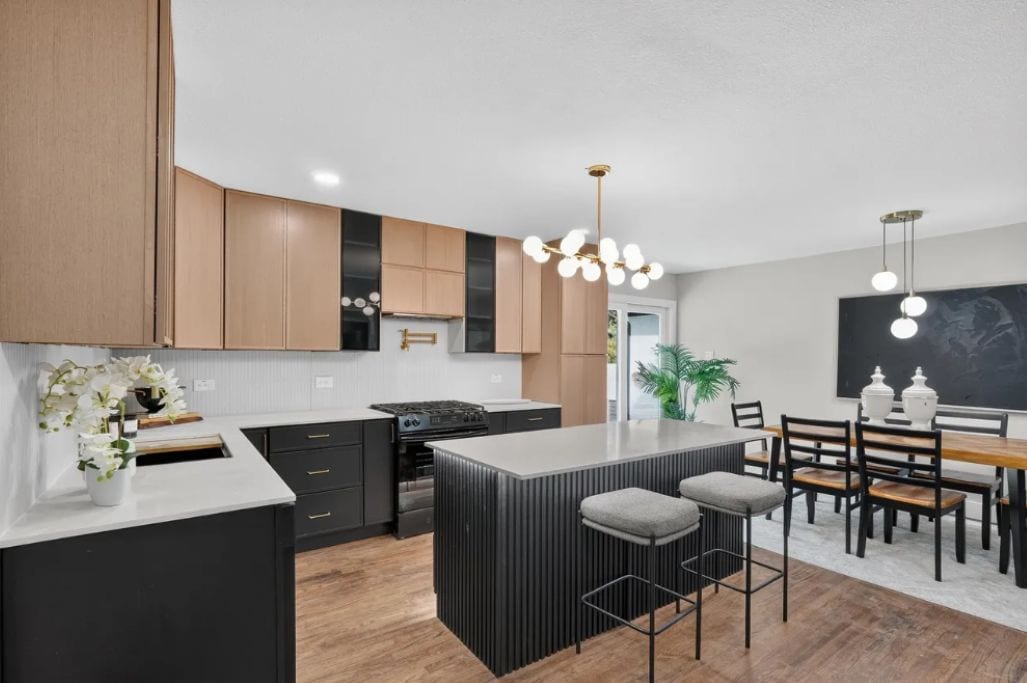 A modern kitchen with a central island, dark cabinetry, and pendant lighting.