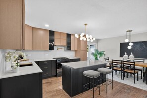 A modern kitchen with a central island, dark cabinetry, and pendant lighting. - Aboretum. White Rock Lake. Modern 3 Br. 6 guests (Dallas)