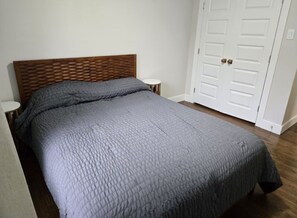 A bedroom with a bed, a wooden headboard, a white door, and a small round table. - Aboretum. White Rock Lake. Modern 3 Br. 6 guests (Dallas)