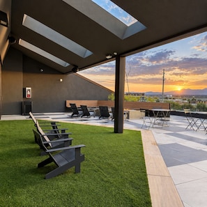 Eine Terrasse im Freien mit Sitzgelegenheiten und Blick auf den Sonnenuntergang.