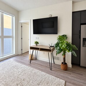 A modern kitchen with a built-in TV, a wooden desk, and a large potted plant. - Downtown SLC Studio | King Bed + Free Parking (Salt Lake City)