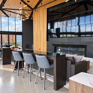 A modern kitchen with a central island, bar stools, and a fireplace. - Downtown SLC Studio | King Bed + Free Parking (Salt Lake City)