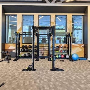 A gym with a squat rack, kettlebells, and exercise balls. - Downtown SLC Studio | King Bed + Free Parking (Salt Lake City)
