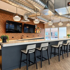 A modern kitchen with a long island, bar stools, and pendant lighting. - Downtown SLC Studio | King Bed + Free Parking (Salt Lake City)