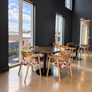A modern dining area with a round table and six chairs, large windows offering a view of the cityscape. - Downtown SLC Studio | King Bed + Free Parking (Salt Lake City)