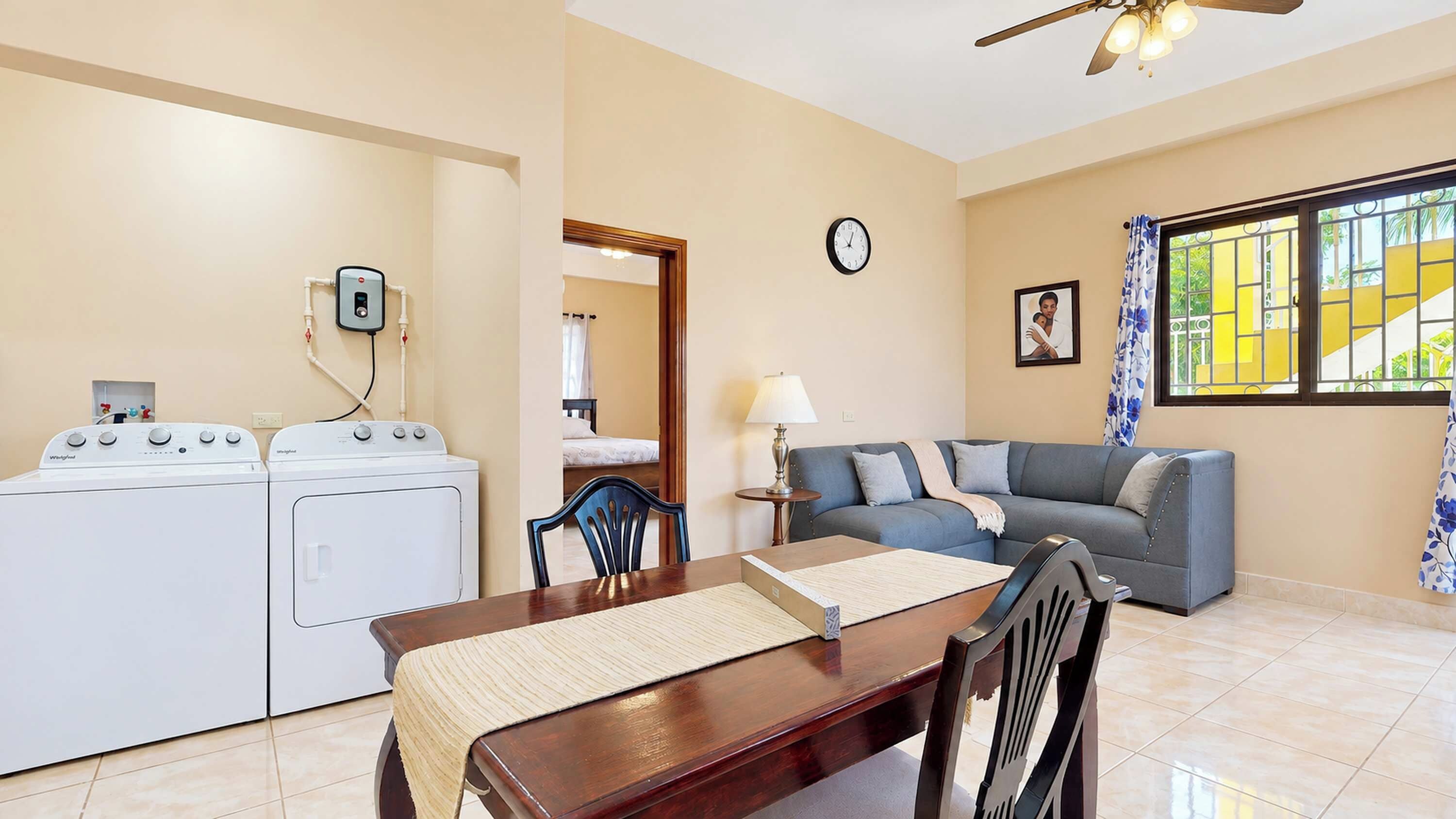 A compact living space with a dining area, a sofa, a table, and a washing machine.