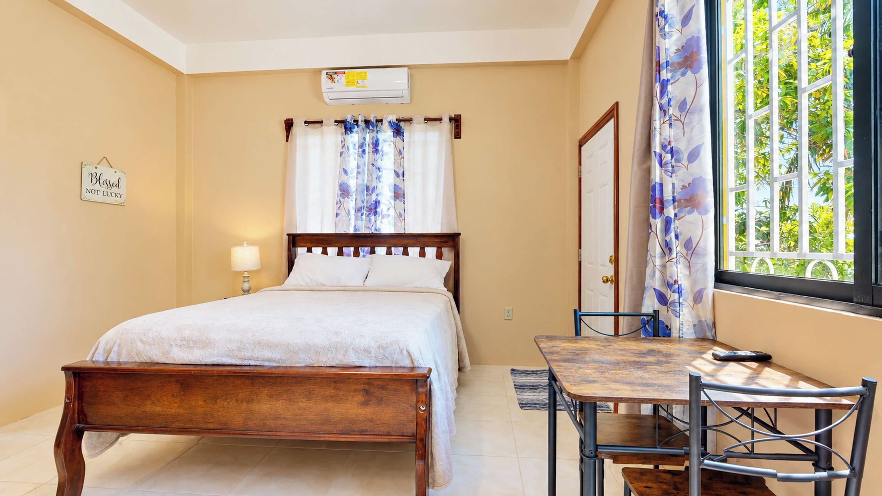 A bedroom with a bed, bedside table, lamp, and a window with curtains.