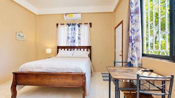 A bedroom with a bed, bedside table, lamp, and a window with curtains.