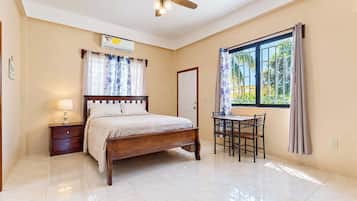 Un dormitorio con cama, mesita de noche y escritorio con sillas.