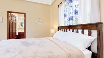 A bedroom with a wooden bed, a bedside lamp, a mirror, and a sign on the wall.