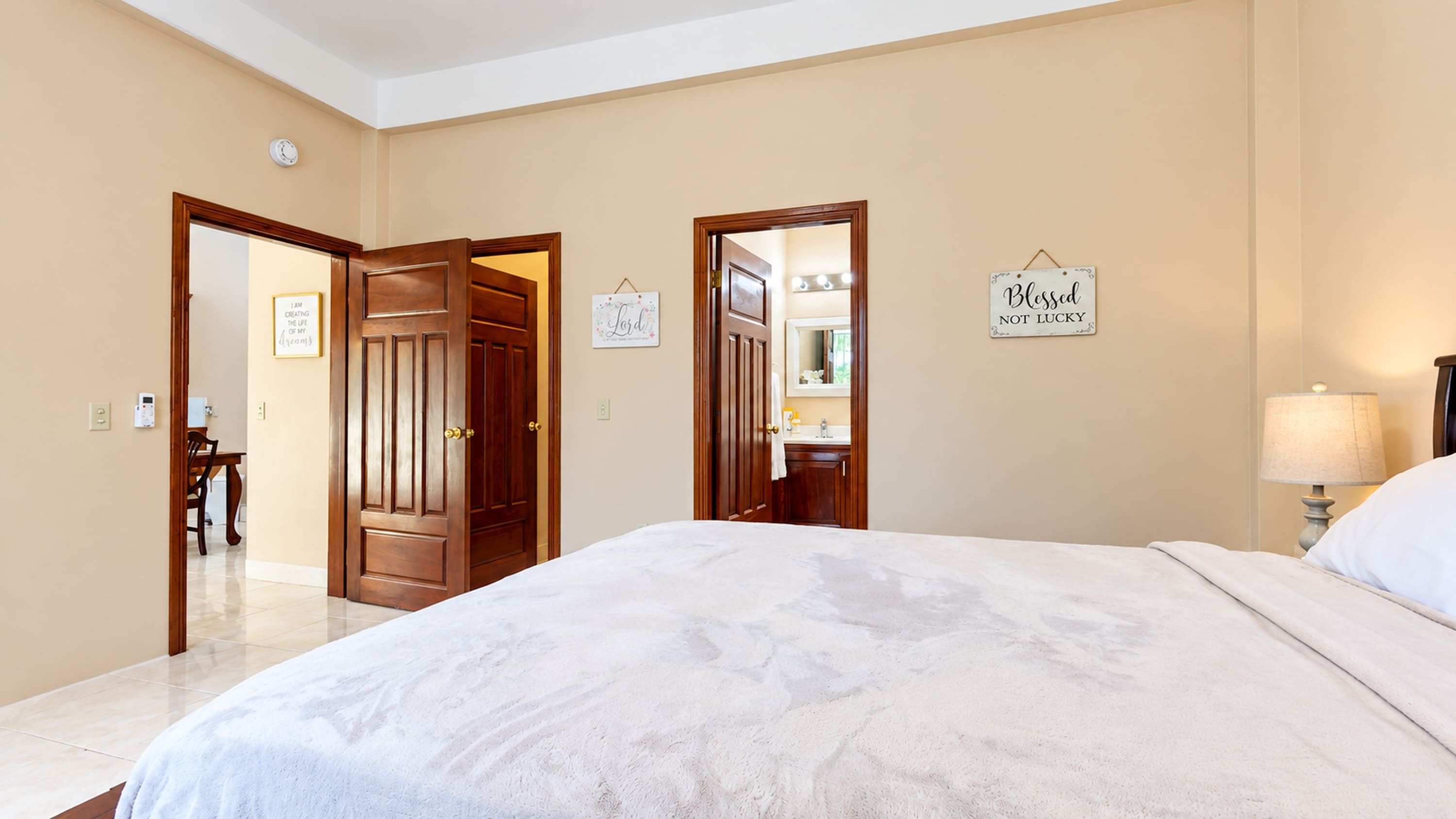 Een hotelkamer met een groot bed, een badkamer met een spiegel en een deur naar een andere kamer.