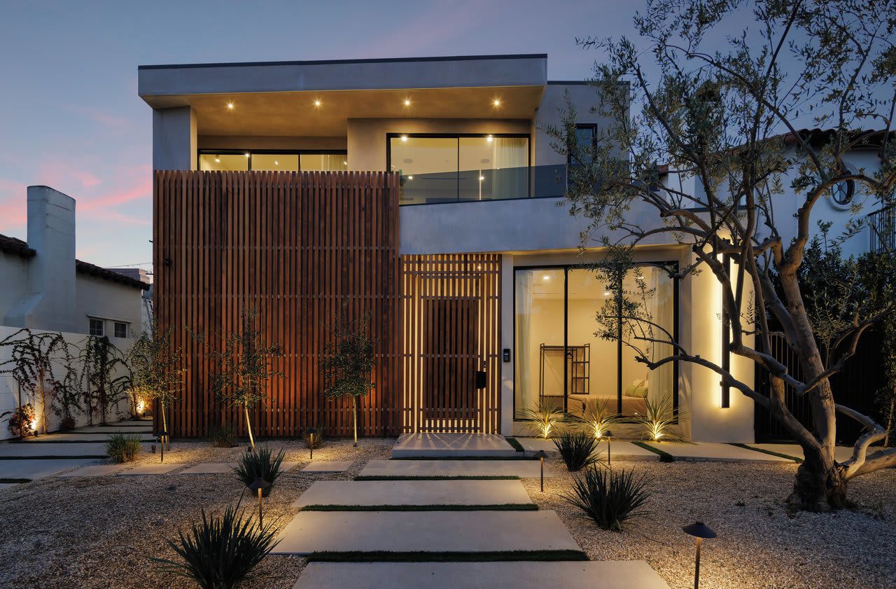 Une maison moderne à deux étages, dotée d’une clôture en bois, d’une allée et d’une entrée bien éclairée.