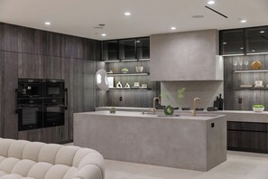 A modern kitchen with built-in appliances, a central island, and a seating area. - Casa Priscilla by Oraklus (Los Angeles)