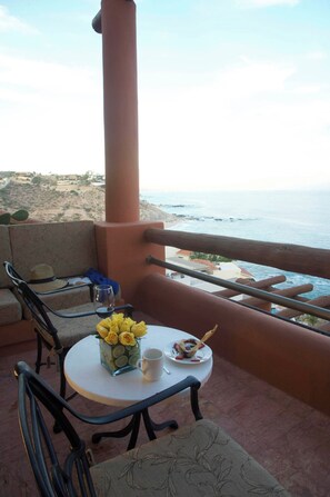 Een balkon met een tafel voor twee personen, met uitzicht op de kust.