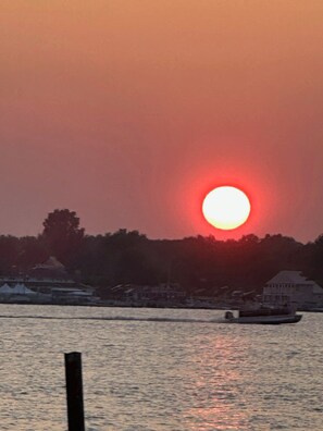 A sunset over a body of water with a silhouette of trees and buildings in the distance. - Charming 3-bedroom house on Buckeye Lake right next door to winery! (Thornville)