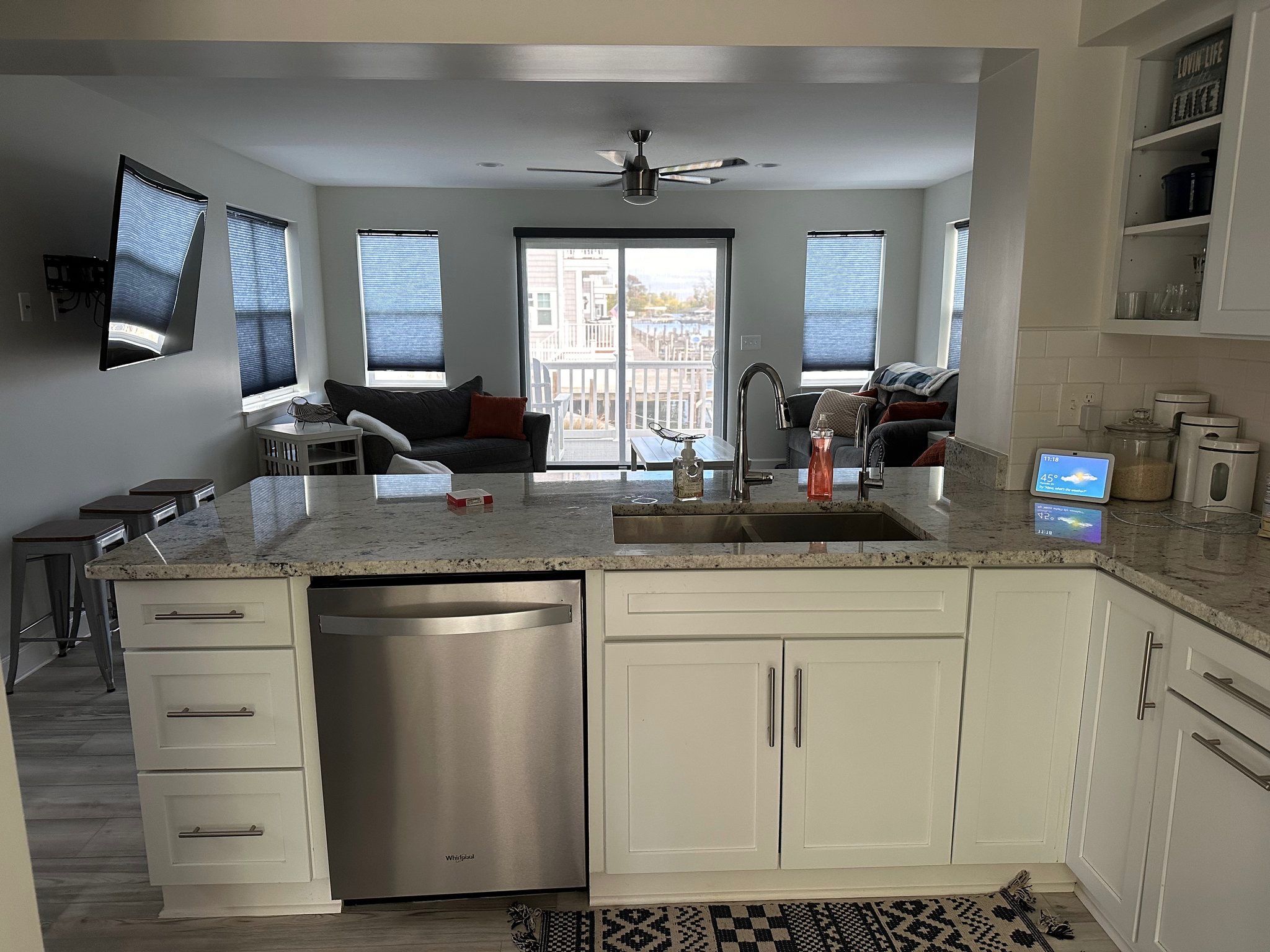 A modern kitchen with a dishwasher, a sink, and a dining area with a table and chairs.