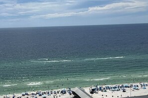 Ein Strand mit Sonnenschirmen und Menschen, ein klarer Himmel und das Meer.