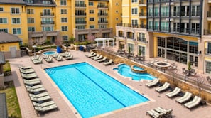 Ett hotell med flera balkonger, en central pool och solstolar.
