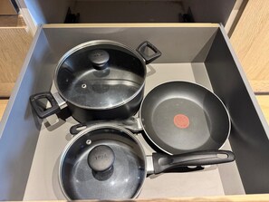 En låda som innehåller tre köksredskap: en stekpanna, en kastrull och en panna.