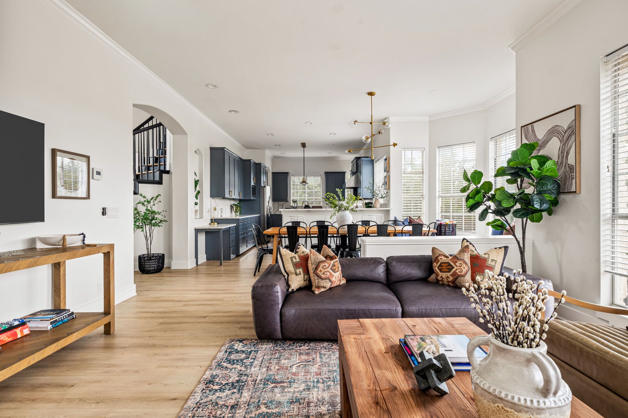 A modern living room with a dark leather sofa, wooden coffee table, and a patterned rug.